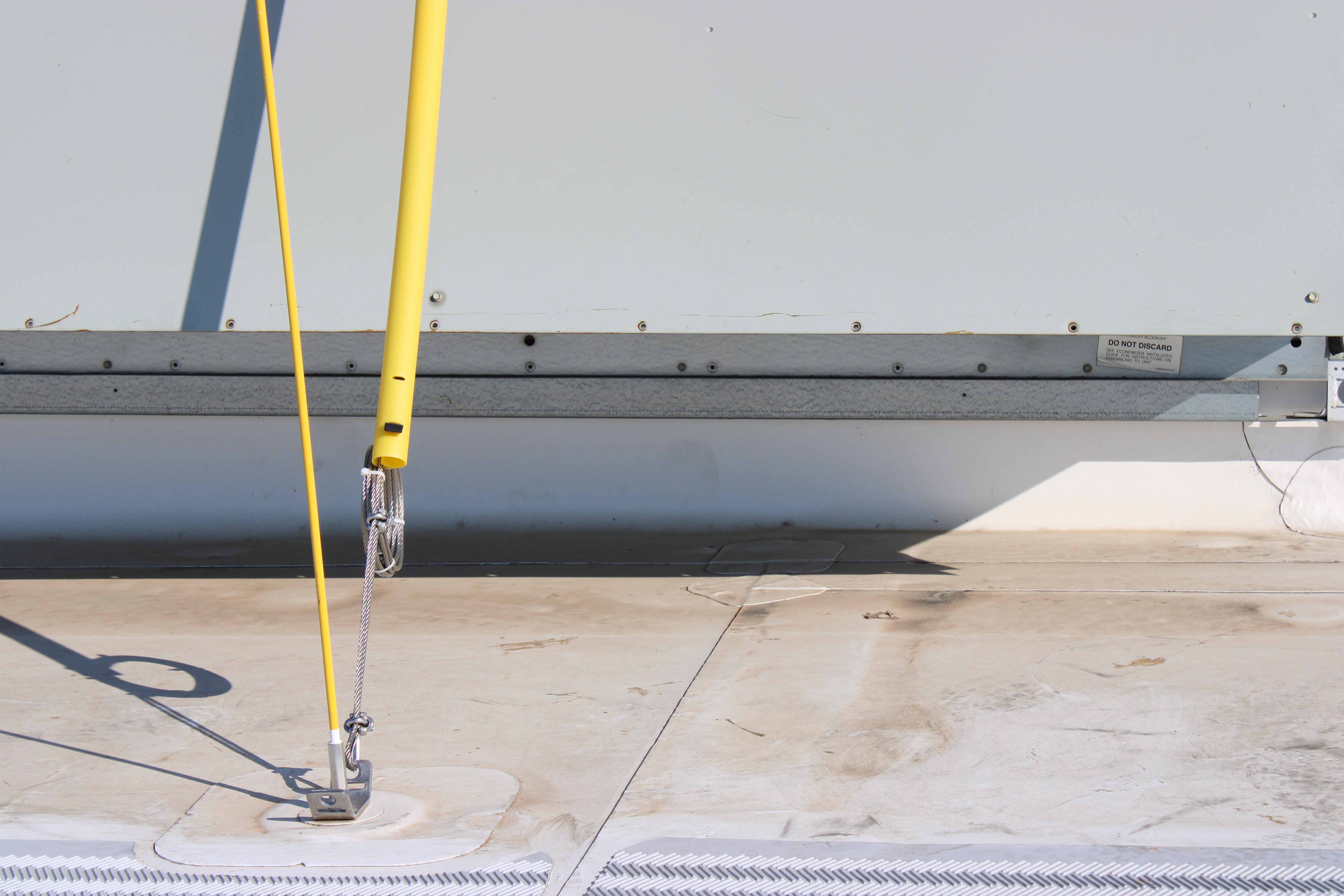 Yellow braces tied down across a white membrane roof