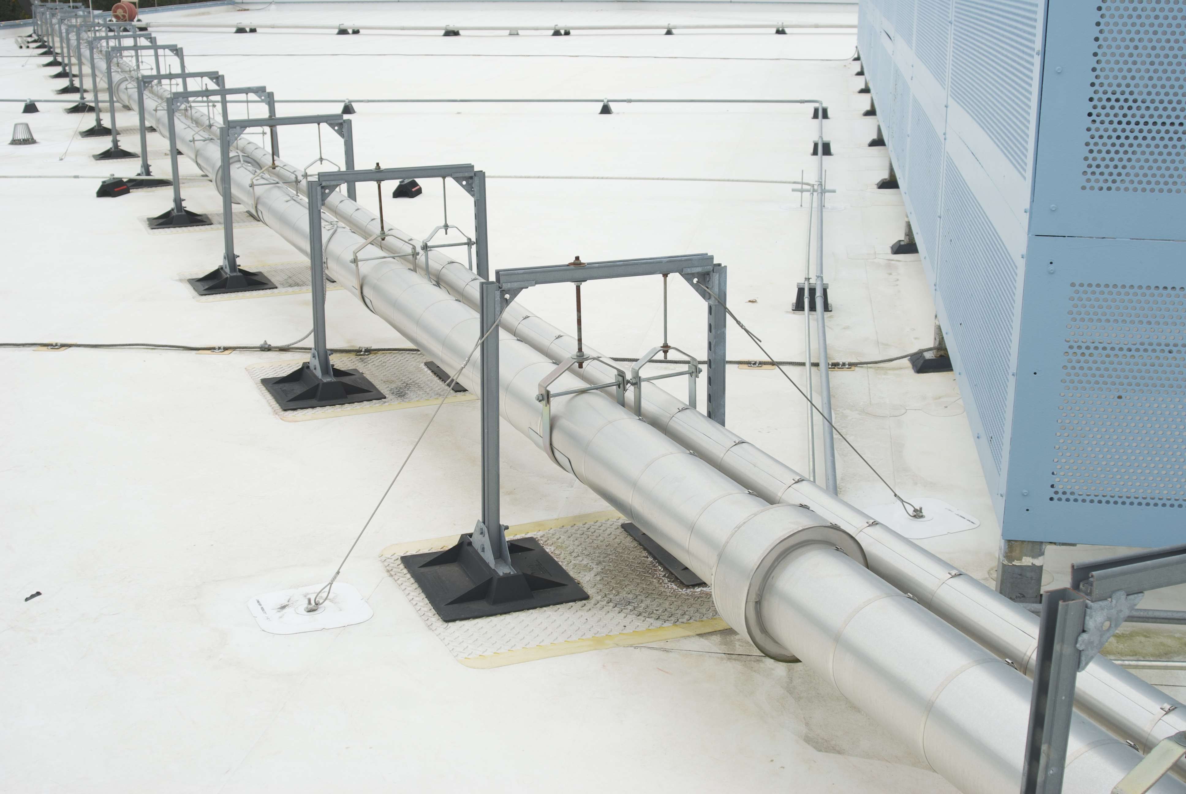 A pipe run carried on fastened supports across a commercial roof